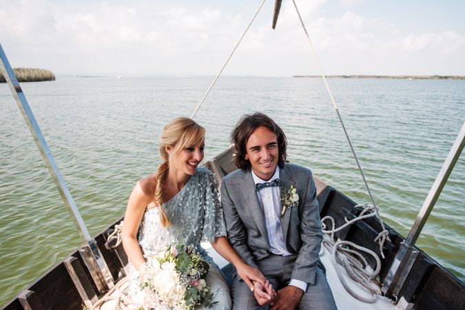Couple holding hands while sitting on boat