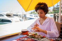 Woman putting salt on salad in cafe on pier bYYyGb