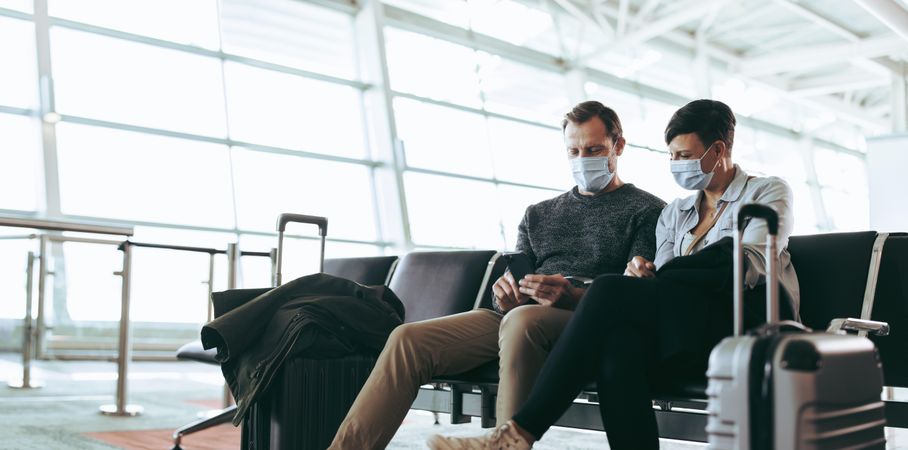 Tourists in face masks in airport wait for flight delayed or cancelled due to covid-19 lockdown