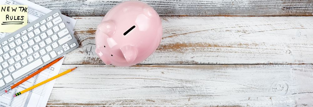 Income tax forms with new changes plus piggy bank on rustic desktop