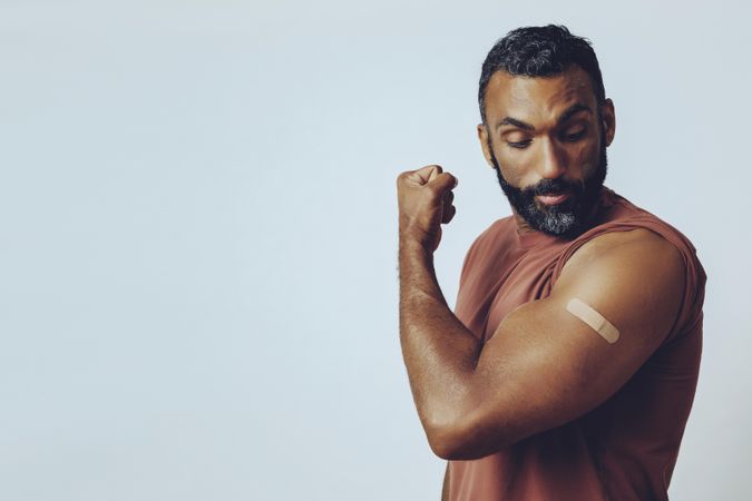 Proud man looking at vaccination on his arm with copy space