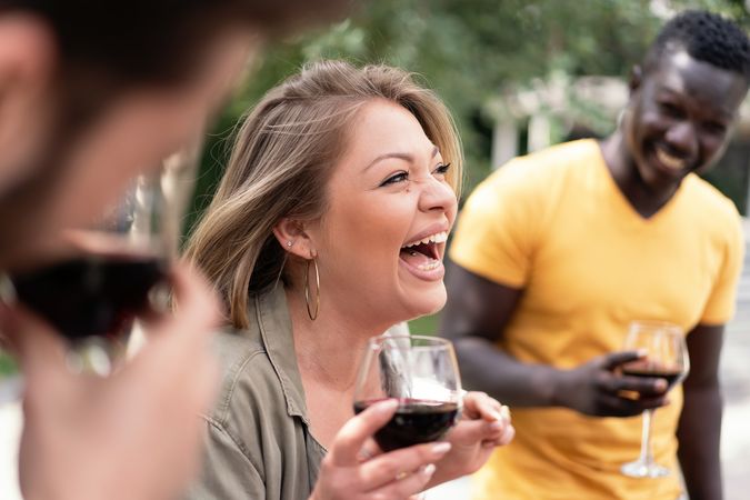 A woman's infectious laughter she holds a glass of red wine