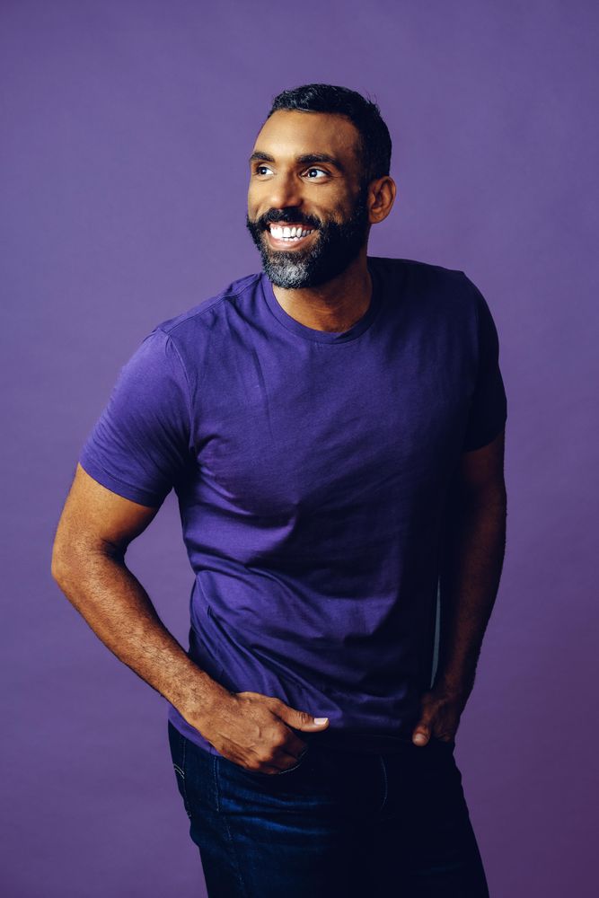 Vertical composition of happy male in purple studio