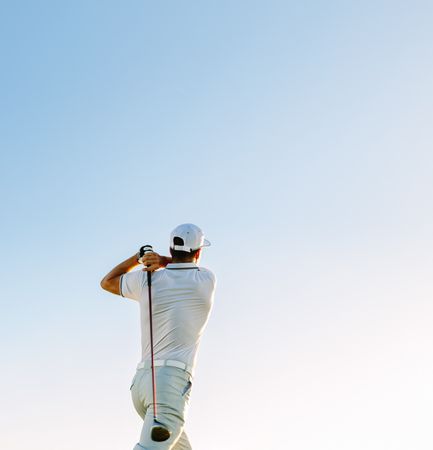 Professional golfer taking shot against clear sky