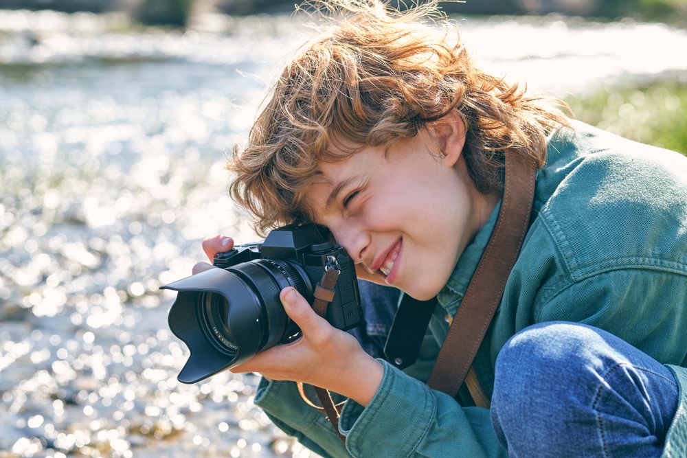 Cheerful boy taking photo on grassy coast