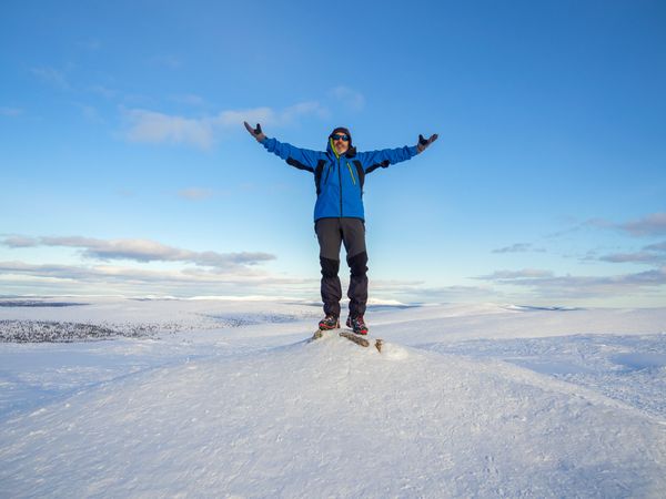 Man with arms raised in celebration on snowy peak