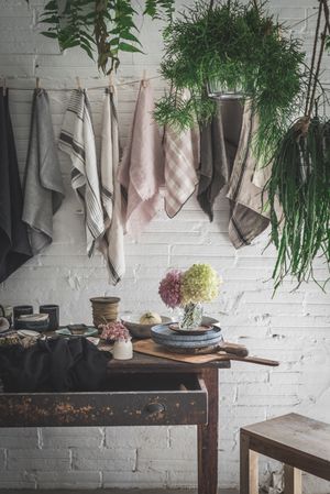 Table with flowers in vase on trays near towels hanging on thread