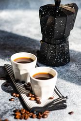 Two shots of espresso on kitchen counter with moka