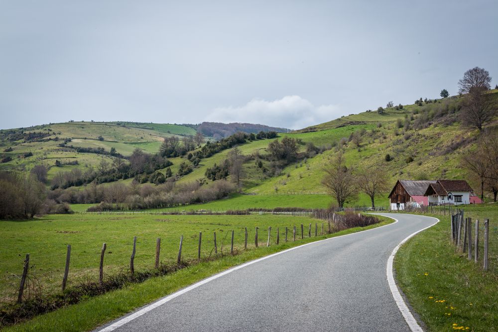 Asphalt road near houses and hills