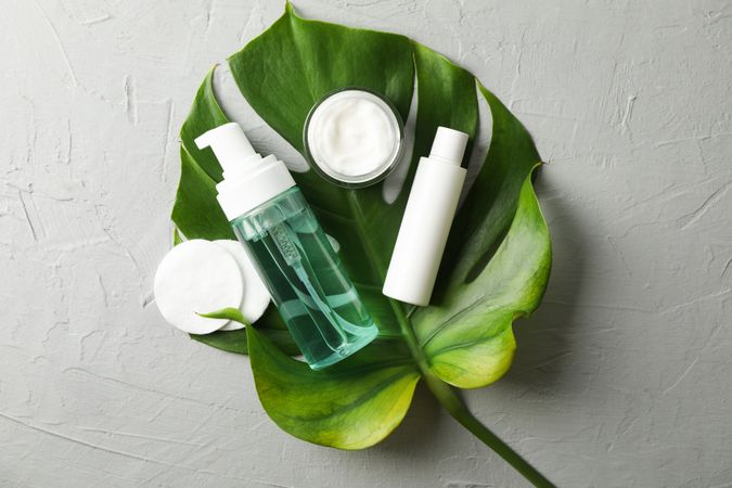 Flat lay with body care accessories and palm leaf on grey background, copy space