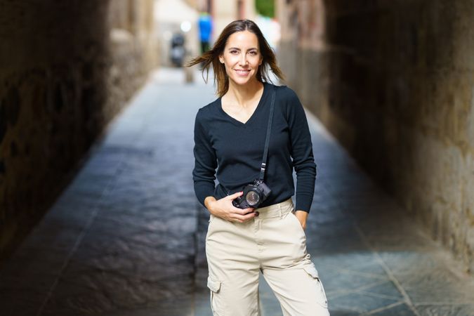 Happy woman holding camera in arch