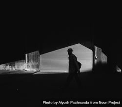 Man walking through shadows in front of garage door on street in stark minimalist shot 432N15