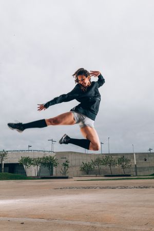 Female dancer in active wear smiling while dancing in jump outdoors