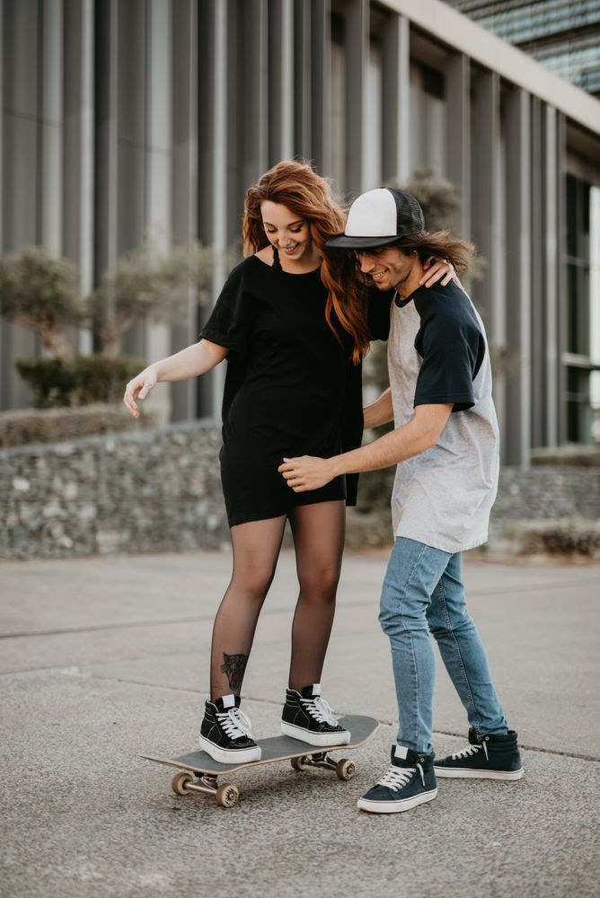 Man helping girlfriend to skate on road