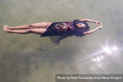 Black woman floating in a pool of water 5lVZ36