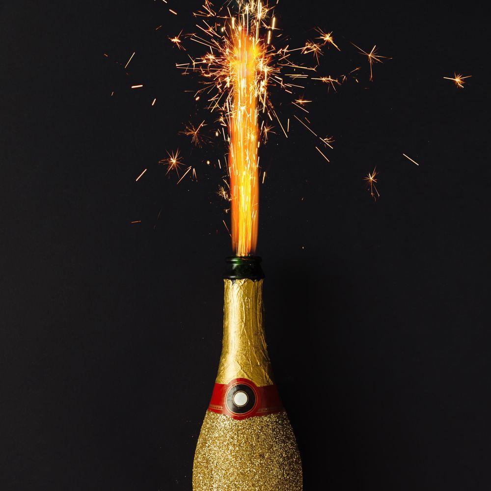 Golden champagne party bottle onbackground with fire sparklers