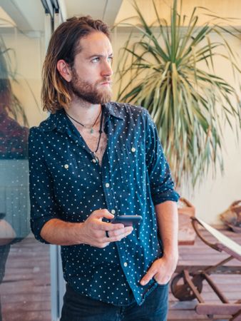 Trendy handsome male with phone on terrace