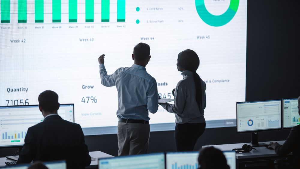 Business Team Analyzes Data on Large Screen.