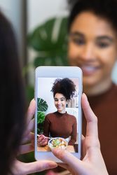 Crop woman taking photo of friend in restaurant