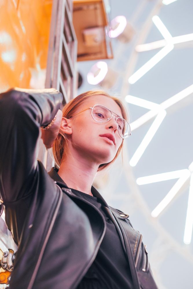 Woman standing at dusk near lit Ferris wheel