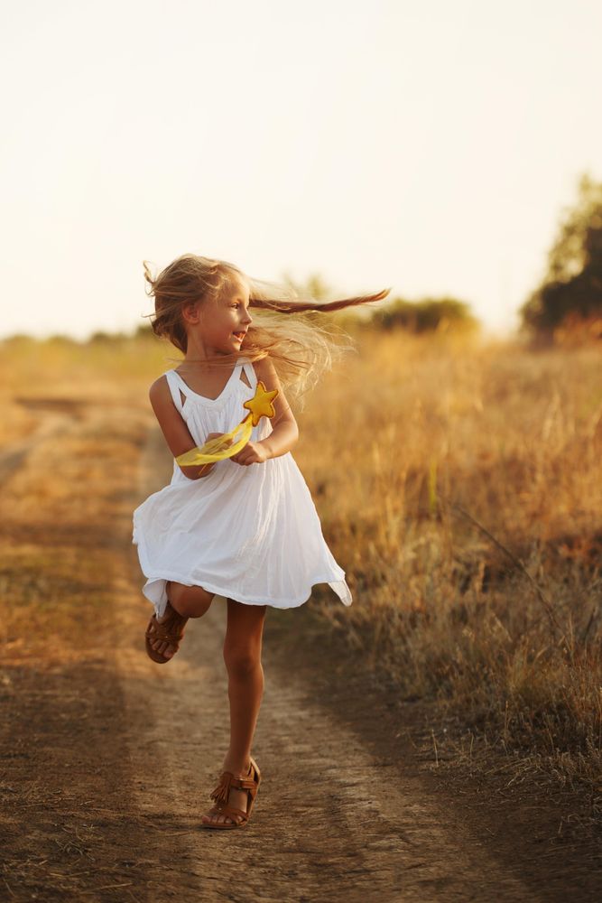 Blonde female child running along rural trail at sunset