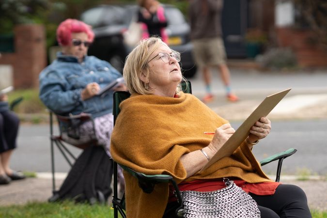 Woman looking up while drawing outside