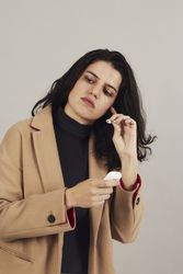 Serious young woman putting on earbuds in studio