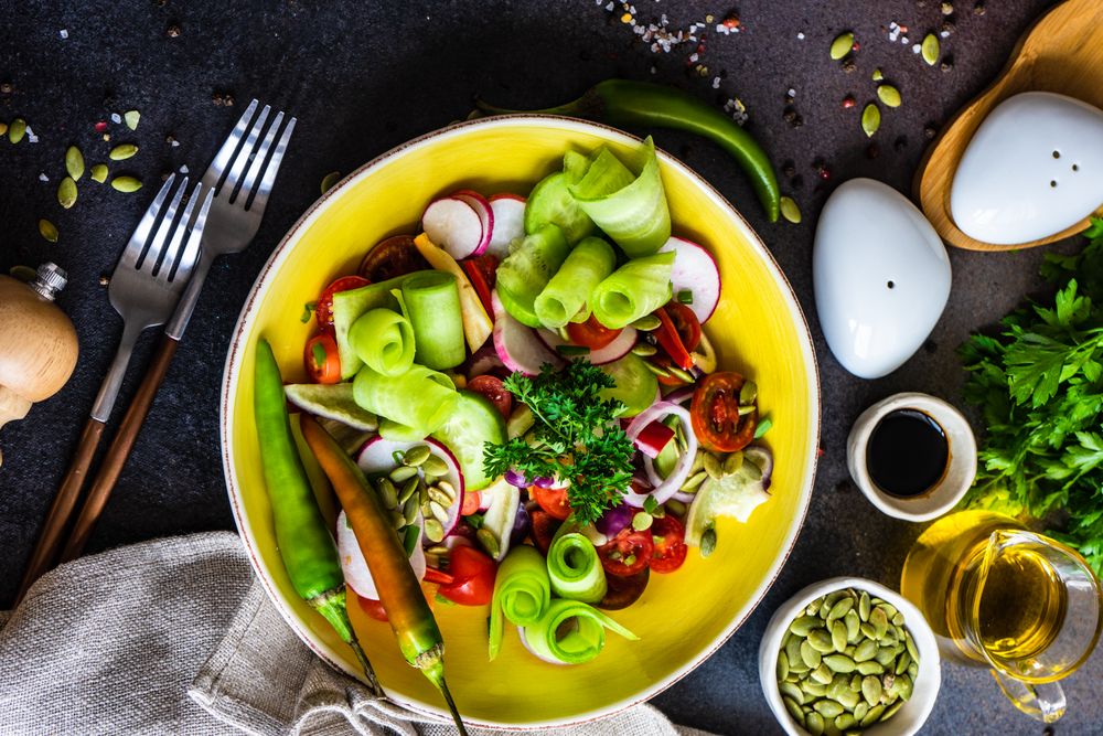 Top view of healthy raw salad with freshly chopped vegetables served with nuts and garnish