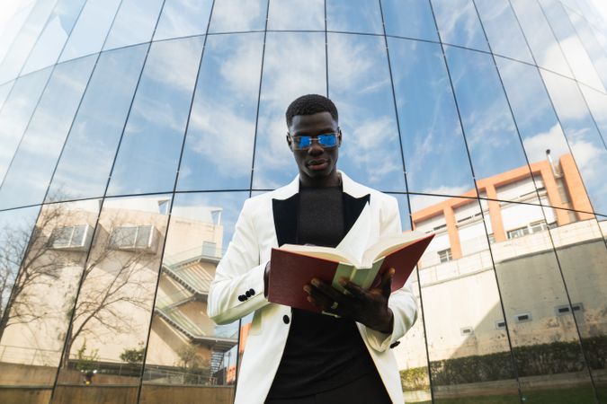 Serious Black businessman reading book in downtown