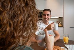 Happy couple talking while eating pastries and drinking coffee at breakfast