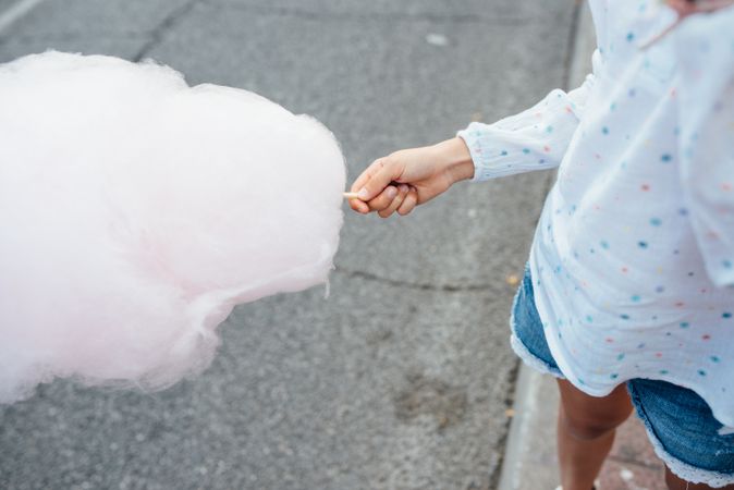 Cheerful girl eating cotton candy on street