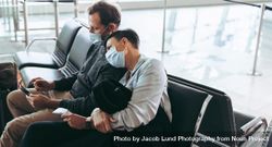 Man and woman traveler during pandemic sitting at airport terminal 5rMRP0
