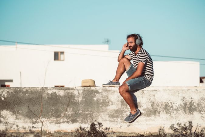 Young male sitting with smartphone and headphones