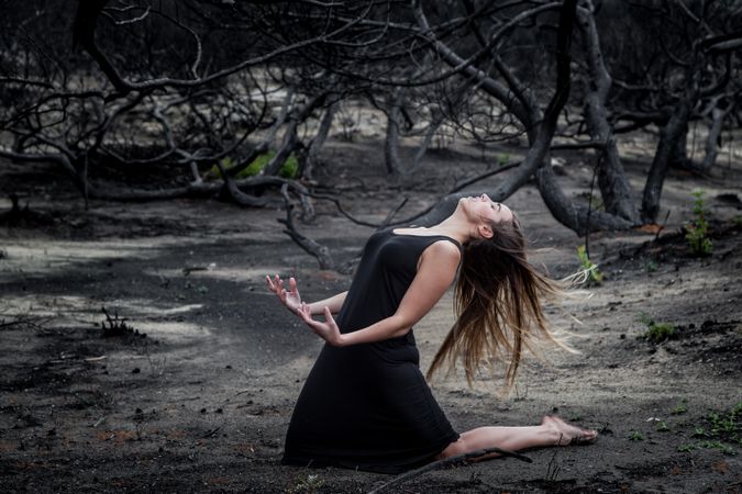 Woman posing on ground near dry trees