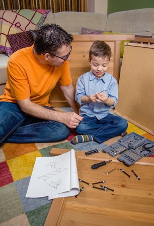Father and son assembling a new furniture for home