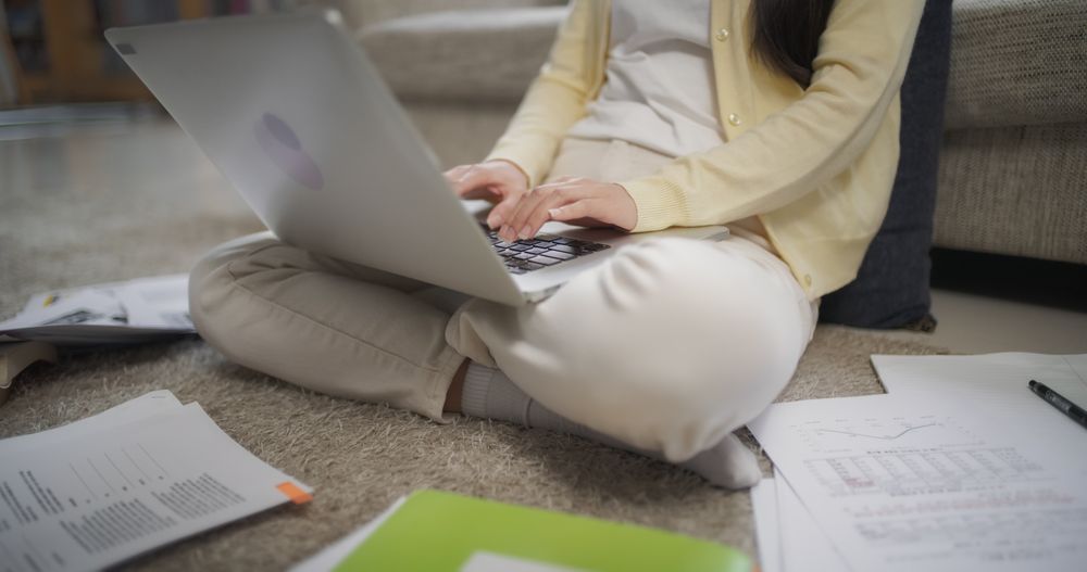 Close Up on Female Student Writing Her Thesis, Browsing Internet for Research, Using Laptop Computer and Notebooks at Home.