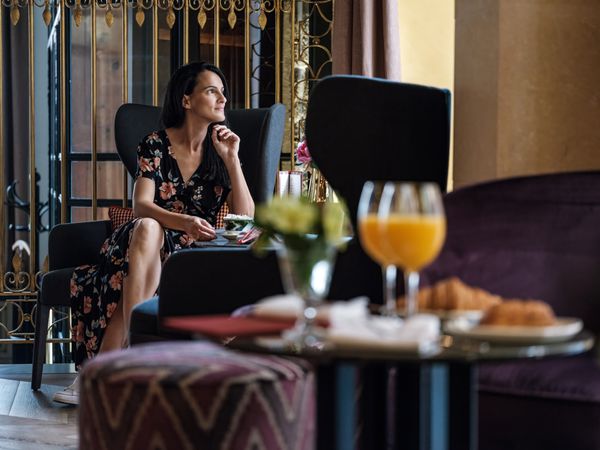 Stylish woman sitting at table in cafe of hotel