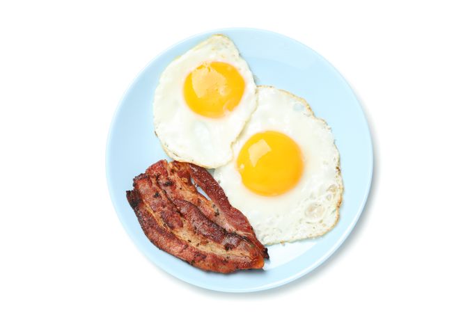 Top view of breakfast plate with fried eggs and bacon