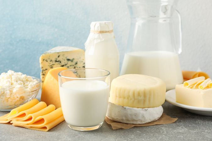 Dairy products on grey table against blue background, copy space
