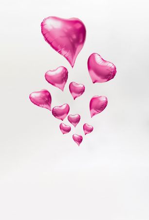 Pink heart balloons on light background