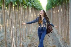 A Joyful Young Woman Happily Walking Among Tall Trees in Beautiful Nature Surroundings