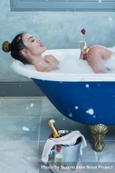 Woman enjoying a glass of champagne in a bathtub 5QYkd5