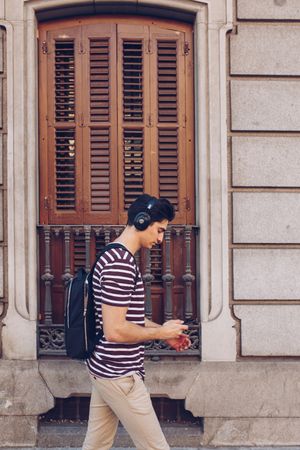 Young man with headphones and smartphone walking outdoors