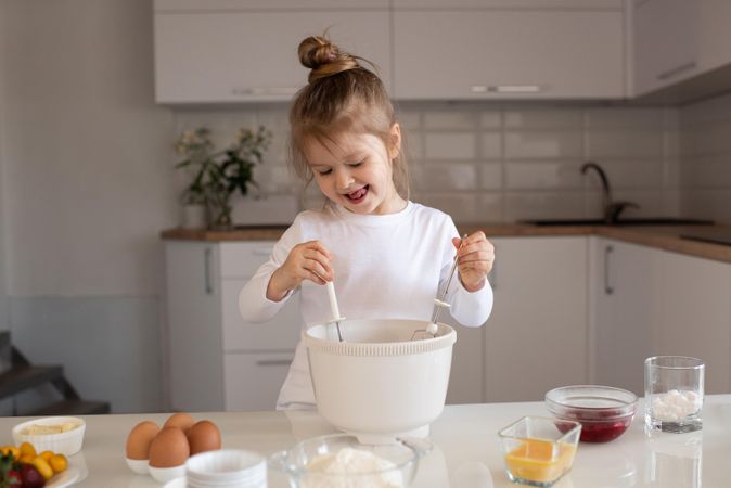 Young girl in light shirt making cupcake in the kitchen