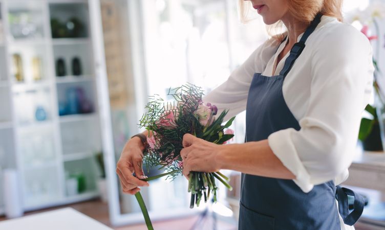 Skillful female florist creating bouquet of flowers
