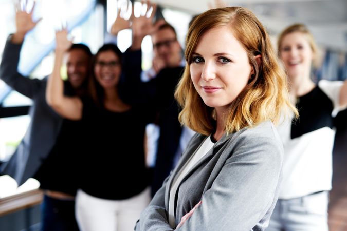 Businesswoman in front of her business associates with their arms in the air