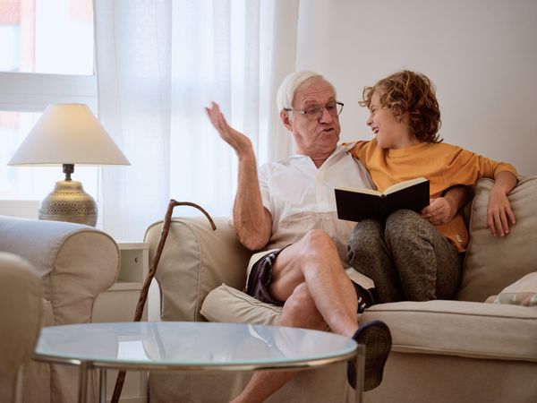 Cheerful boy with grandfather reading book