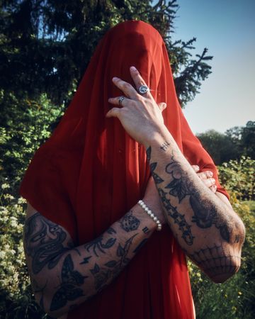 Tattooed male with red sheet on his head