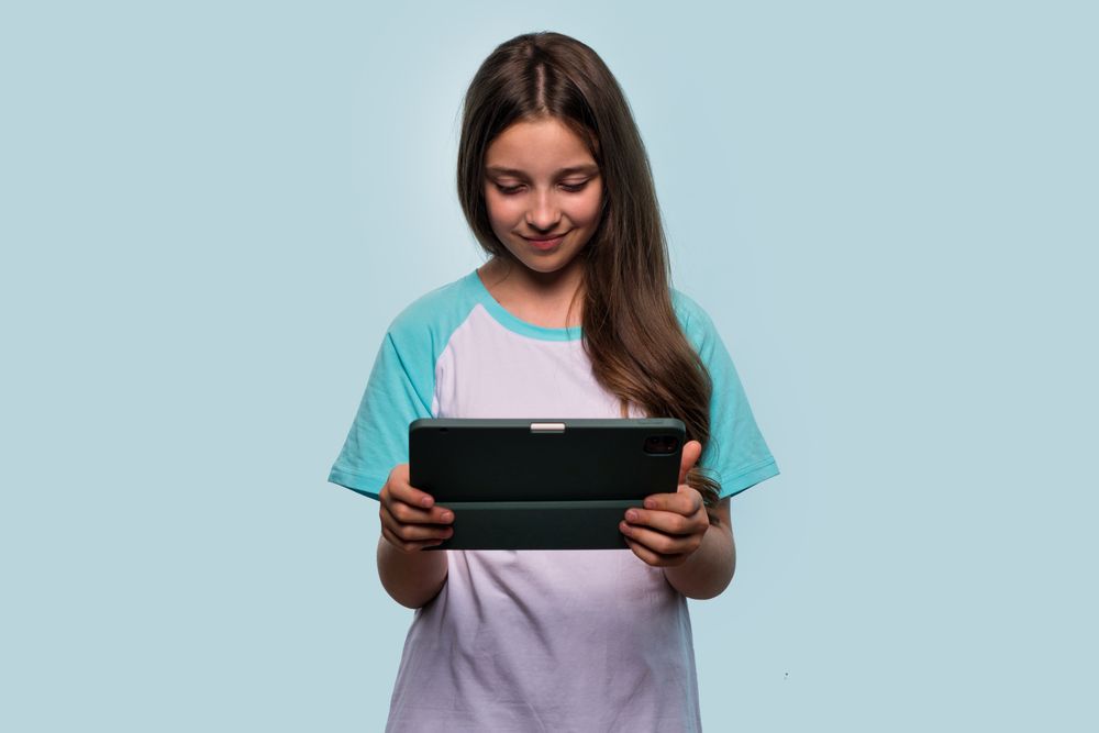 Girl focused on using tablet, possibly for gaming or studying.