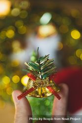 Cropped image of two fingers holding a Christmas bell ornament 47qPz0